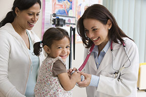 image of Toddler girl laughing while doctor examines